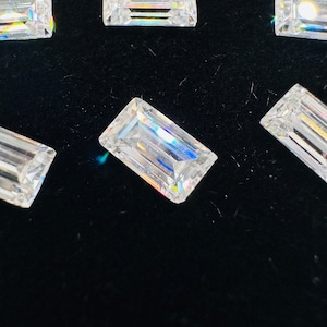 May include: A collection of clear, rectangular, faceted gemstones on a black velvet background.