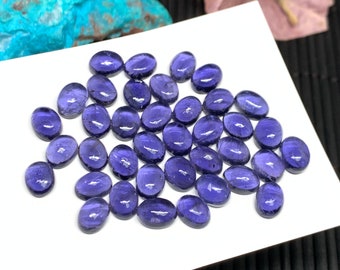 May include: A collection of 25 oval-shaped, purple amethyst gemstones. The gemstones are smooth and polished, with a slight sheen.