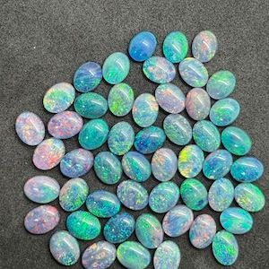 May include: A collection of oval-shaped opal gemstones in various shades of blue, green, and white. The opals have a shimmering, iridescent effect.