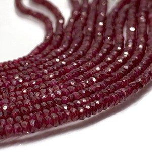 May include: A strand of deep red ruby beads, faceted and polished, strung together in a long, continuous line. The beads are small and uniform in size, creating a smooth and elegant look.