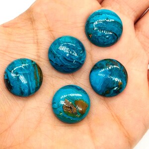 May include: Five round, polished gemstones with a vibrant turquoise hue and brown inclusions. The stones are smooth and appear to be cabochons, perfect for jewelry making or crafting projects. The gemstones are displayed on a light background.