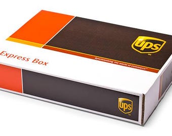 May include: A rectangular cardboard shipping box with a white base, featuring orange and dark brown panels. The top and side display the UPS logo in yellow and brown, with the text Express Box and Synchronizing the world of commerce printed.