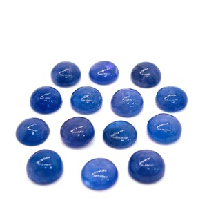 May include: A collection of fourteen round, polished blue gemstones. The stones vary slightly in shade, ranging from deep indigo to lighter shades of blue. They are arranged against a plain white background, highlighting their color and shape.