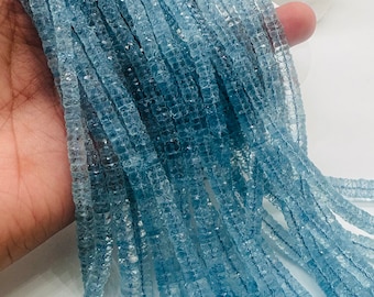 May include: A strand of light blue aquamarine gemstone beads. The beads are faceted and have a slightly irregular shape. The beads are strung on a clear thread.