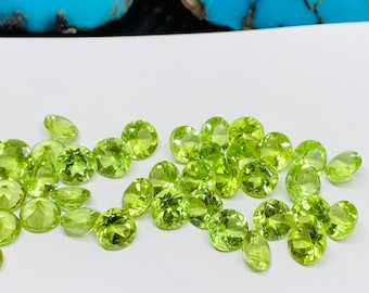 Puede incluir: Un grupo de 25 piedras preciosas de peridoto redondas y verdes. Las piedras son facetadas y tienen un color verde claro.