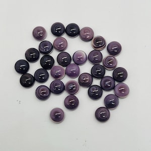 Puede incluir: Una colección de 20 cabujones de concha púrpura y blanca. Los cabujones son redondos y tienen una superficie lisa y pulida. Son perfectos para la elaboración de joyas u otros proyectos de artesanía.