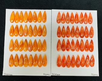 Könnte beinhalten: Zwei Sätze orangefarbener, tropfenförmiger Edelsteine, jeweils auf einer weißen Karte angeordnet. Die Edelsteine sind 7x20mm groß und haben ein poliertes, durchscheinendes Aussehen. Jede Karte ist mit der Menge von 32 Stück beschriftet.