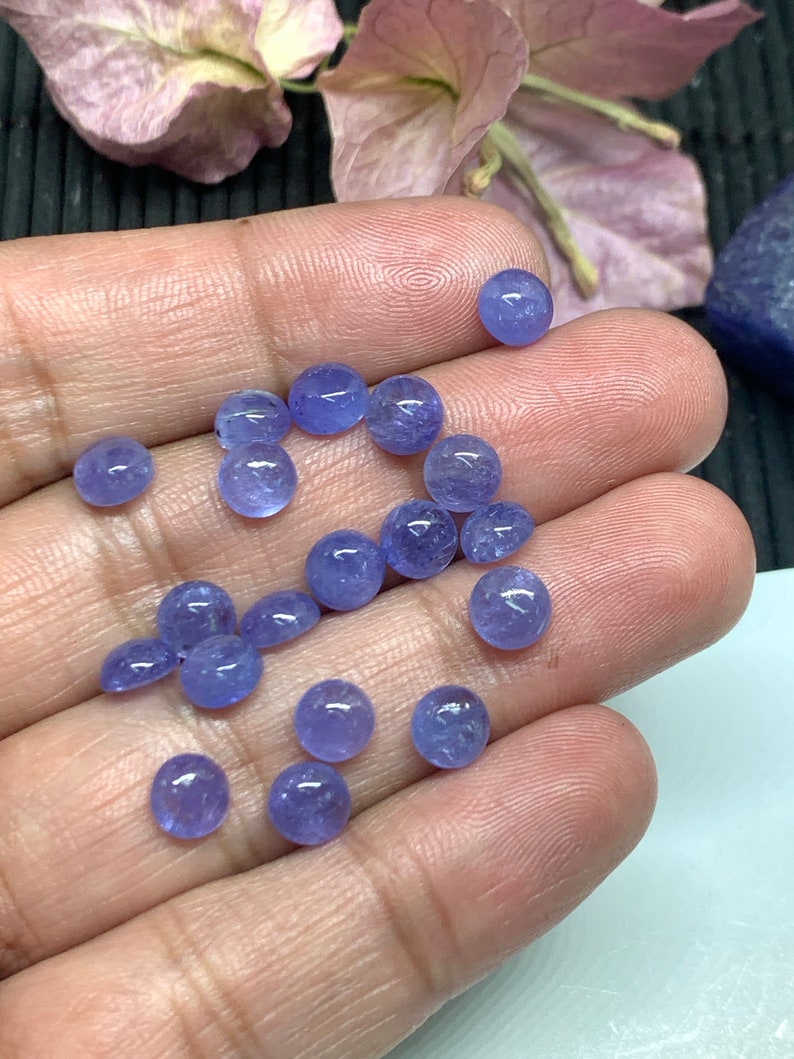 May include: A collection of round, light blue gemstones, likely amethyst or blue topaz, in various sizes. The gemstones are smooth and polished, with a slight sparkle.