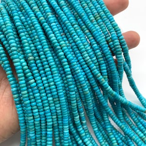 May include: A strand of turquoise beads, each bead is a vibrant blue color and has a slightly rounded shape. The beads are strung together on a clear thread.