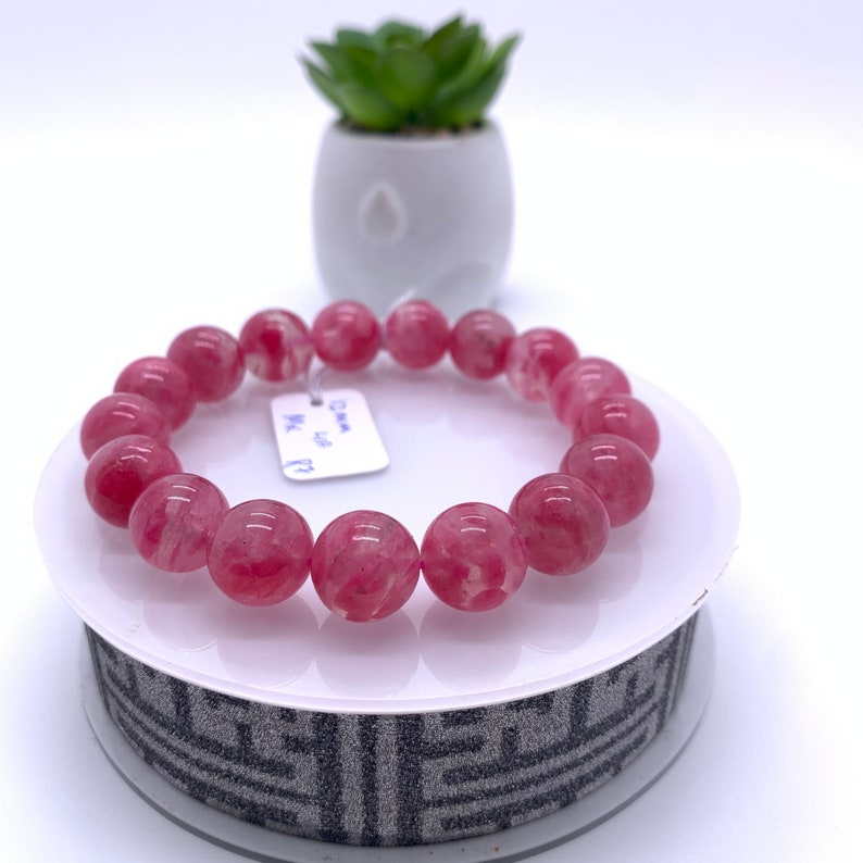 May include: A pink and white gemstone bracelet with a tag that says "Dawn MC. 5.5"