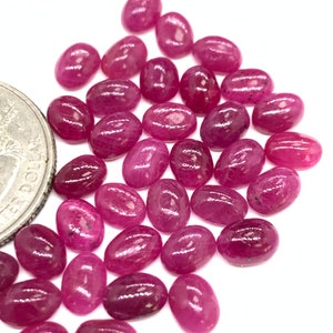Puede incluir: Un mont&oacute;n de piedras preciosas de rub&iacute; rosa de forma ovalada. Las piedras son lisas y pulidas, con un ligero brillo.