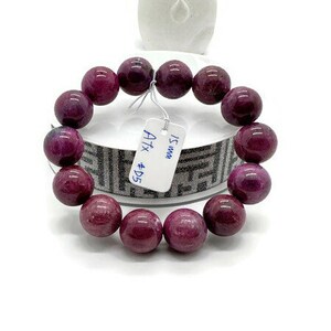 May include: A purple gemstone bracelet with 15 mm beads. The bracelet has a tag that reads "15 mm  A1x #D5".