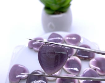 May include: A collection of purple heart-shaped seashells. The shells have a swirling pattern and a glossy finish.