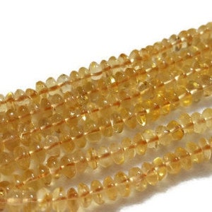 May include: A strand of golden yellow citrine gemstone beads. The beads are faceted and have a slightly irregular shape. The beads are strung on a clear thread.