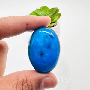 May include: A smooth, oval-shaped blue gemstone with white and grey swirls and a dark blue centre.