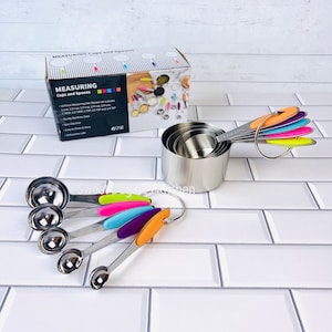 May include: A set of stainless steel measuring cups and spoons with colorful silicone handles. The set includes 1/4 cup, 1/3 cup, 1/2 cup, 1 cup, 1/8 tsp, 1/4 tsp, 1/2 tsp, 1 tsp, and 1 tbsp. The cups and spoons are nested together and have a ring for easy storage.