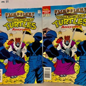 May include: Two comic book covers featuring Teenage Mutant Ninja Turtles. The covers are blue and green with the title "Blindsight" and "Teenage Mutant Ninja Turtles Adventures".