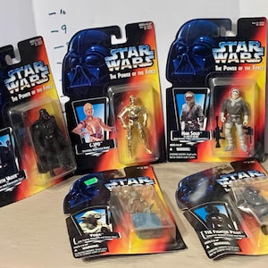 May include: A collection of Star Wars action figures from the Power of the Force series. The figures include Darth Vader, C-3PO, Han Solo, Yoda, and a Tie Fighter Pilot. The figures are packaged in their original boxes.