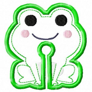 May include: Green felt applique of a smiling frog with black eyes, pink cheeks, and a white body. The frog is sitting with its legs crossed and has a hole in the center.