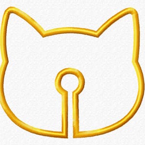 Op de afbeelding: Geborduurd gouden kattengezichtontwerp met een sleutelgatvorm in het midden. De oren van de kat zijn puntig en het sleutelgat heeft een cirkelvormige bovenkant. Het ontwerp is gestikt op een witte stof.