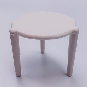 May include: A white, three-legged table with a round top. The table is made of plastic and is approximately 15 cm in diameter.