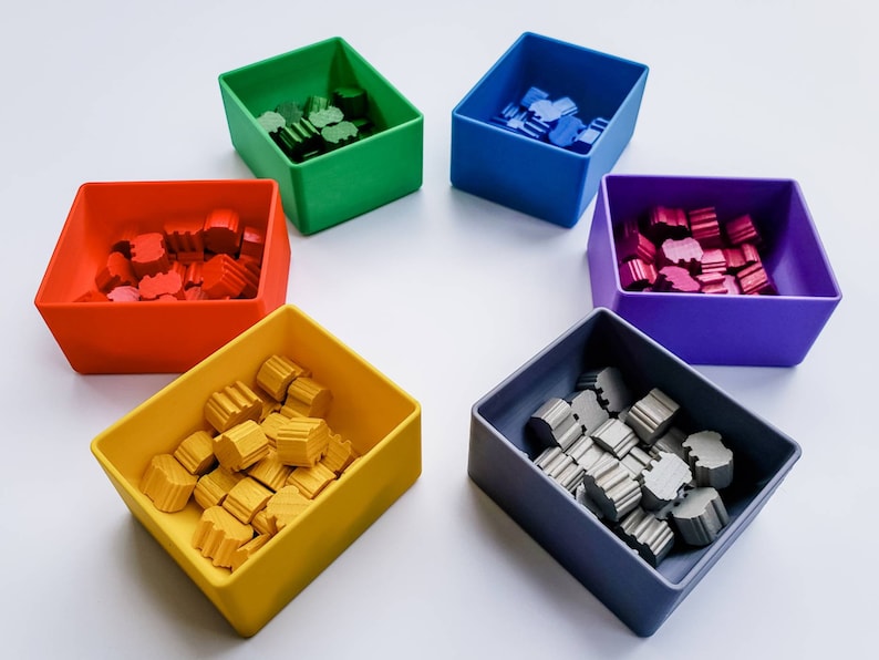 May include: Six small square containers, each filled with colourful wooden pieces. The containers are red, green, blue, purple, yellow, and grey.