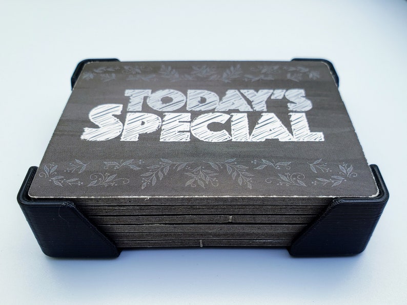May include: A stack of wooden signs with a black frame. The top sign has a grey background with white text that reads "TODAY'S SPECIAL".