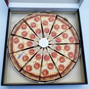 May include: A circular pizza pie divided into 12 slices, each with pepperoni and cheese. The pizza is in a box with the words "New York Slice" printed on the side.