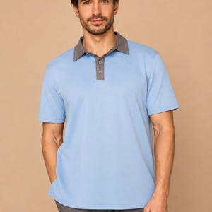 May include: A short-sleeved polo shirt in light blue featuring a contrasting dark gray collar and a buttoned placket. The shirt is paired with dark gray trousers, creating a two-toned ensemble with a clean, structured appearance and simple design.