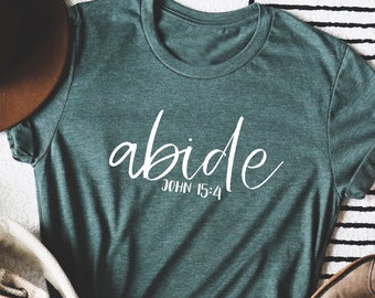 May include: A green t-shirt with the word "abide" in white cursive lettering and the text "JOHN 15:4" underneath.