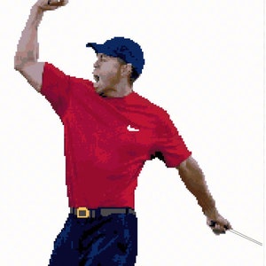 Könnte beinhalten: Ein Golfer in einem roten Shirt, einer blauen Mütze und einer blauen Hose hebt seinen Arm in Triumph. Er hält einen Golfschläger in seiner rechten Hand.