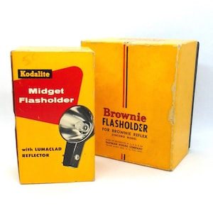 May include: Two boxes for flashbulbs. The smaller box is yellow with red lettering and says "Kodalite Midget Flasholder with LUMACLAD REFLECTOR". The larger box is yellow with black lettering and says "Brownie FLASHOLDER FOR BROWNIE REFLEX SYNCHRO MODEL MADE IN ROCHESTER, N.Y.U.S.A. EASTMAN KODAK COMPANY TRADE MARK REG. U.S. PAT. OFF."