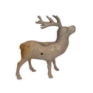 May include: A white ceramic reindeer figurine with a detailed, textured surface. The reindeer has a long neck and large antlers.