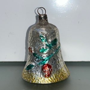 May include: A silver glass bell Christmas ornament with a textured surface and green and red painted floral designs.