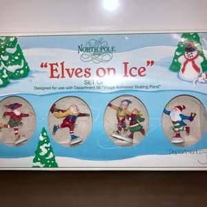 Könnte beinhalten: Ein Karton mit "Elves on Ice"-Figuren aus der North Pole-Serie. Das Set enthält vier Eselfiguren, die auf einem Teich Schlittschuh laufen, mit einem Schneemann und einem Hund im Hintergrund. Die Box ist mit Winterlandschaft dekoriert.