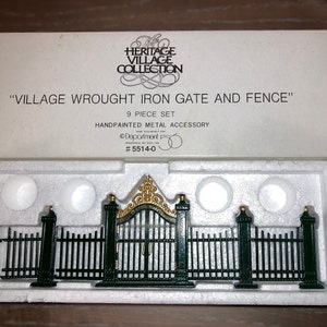 May include: A 9-piece hand-painted metal village wrought iron gate and fence set. The set includes a gate and four fence sections. The gate and fence are black with gold accents. The set is packaged in a white box with the text "Village Wrought Iron Gate and Fence" and "#5514-0".
