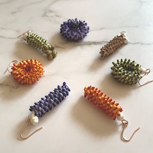May include: Six pairs of handmade earrings featuring various colors and textures. The earrings are made with small, colorful beads and are designed in a variety of shapes, including circles, spirals, and teardrops.