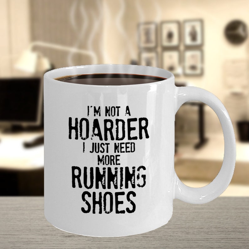 May include: White ceramic coffee mug with black text that reads "I'm not a hoarder I just need more running shoes".