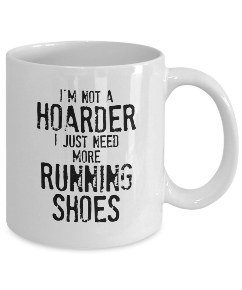May include: White ceramic coffee mug with black text that reads "I'm not a hoarder I just need more running shoes".