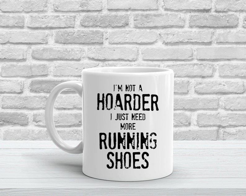 May include: White ceramic mug with black text that reads "I'm not a hoarder I just need more running shoes".