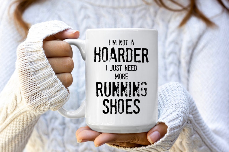 May include: White ceramic coffee mug with black text that reads "I'm not a hoarder I just need more running shoes".