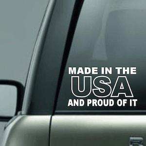 May include: White vinyl decal with the text "MADE IN THE USA AND PROUD OF IT" on a car window. The decal is in a bold, sans-serif font.
