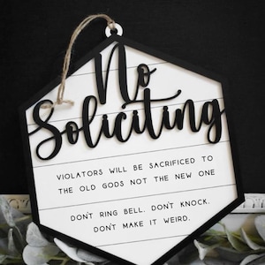Peut inclure: Une pancarte hexagonale blanche avec des lettres noires qui indiquent "No Soliciting". La pancarte a une bordure noire et une ficelle pour l'accrocher. La pancarte comprend &eacute;galement le texte "Violators will be sacrificed to the old gods not the new one. Don't ring bell. Don't knock. Don't make it weird."