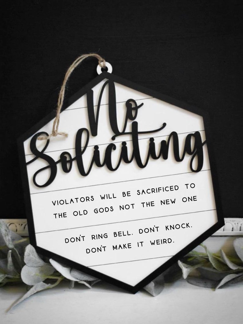 Peut inclure: Une pancarte hexagonale blanche avec des lettres noires qui indiquent "No Soliciting". La pancarte a une bordure noire et une ficelle pour l'accrocher. La pancarte comprend &eacute;galement le texte "Violators will be sacrificed to the old gods not the new one. Don't ring bell. Don't knock. Don't make it weird."