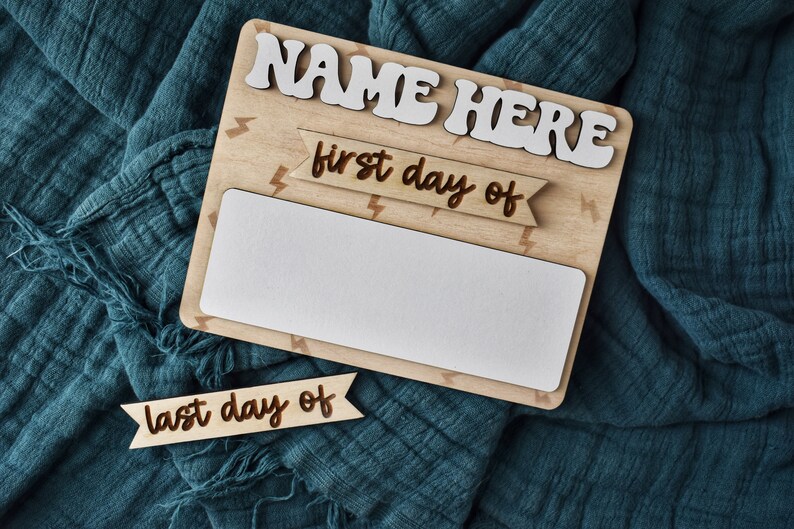 May include: Wooden sign with the text "NAME HERE" in white letters. The sign has a white space for writing in the middle and two banners with the text "first day of" and "last day of" in brown letters.