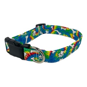 May include: A blue, green, yellow and red tie-dye dog collar with white paw prints and bone designs.