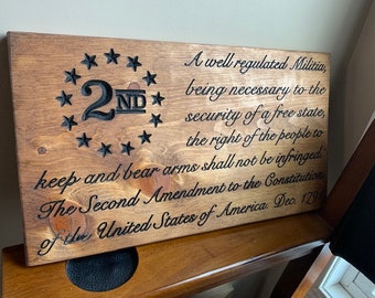 May include: A wooden sign with the text "A well regulated Militia, being necessary to the security of a free state, the right of the people to keep and bear arms shall not be infringed. The Second Amendment to the Constitution of the United States of America, Dec. 1791" and a star-shaped design with the number "2ND" in the center.