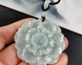 May include: A jade pendant in the shape of a flower with a light green color. The pendant is carved with intricate details and has a smooth, polished finish.