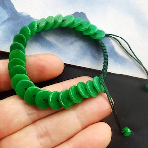 Könnte beinhalten: Ein grünes Jadearmband mit einer Schnurverschlusses. Das Armband besteht aus runden Jadeperlen.