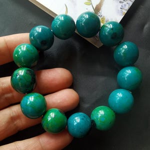 May include: A bracelet made of green and blue gemstone beads. The beads are round and have a smooth, polished finish.